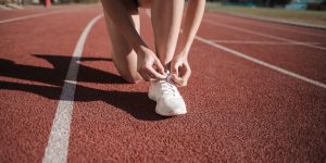 Close-up of a woman tying her shoes on a running track, ready to sprint.