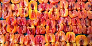 From above of pile of fresh ripe juicy halved persimmons placed on stall and sun drying